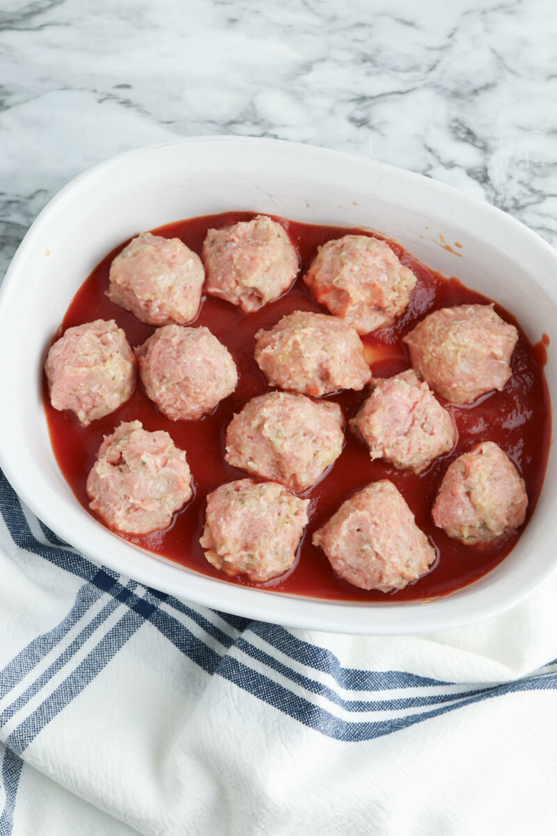 Formed meatballs on top of tomato sauce.